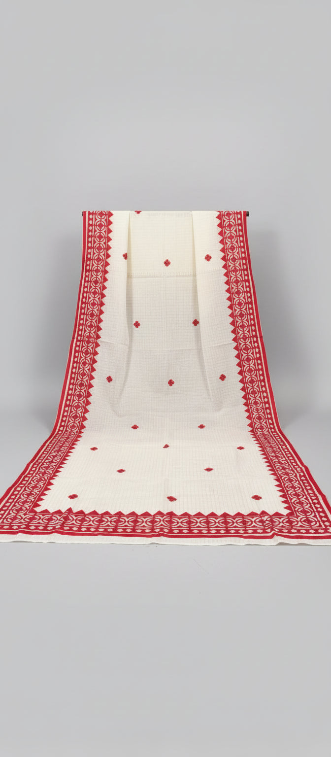 White saree with red border and patterns on a wooden floor.