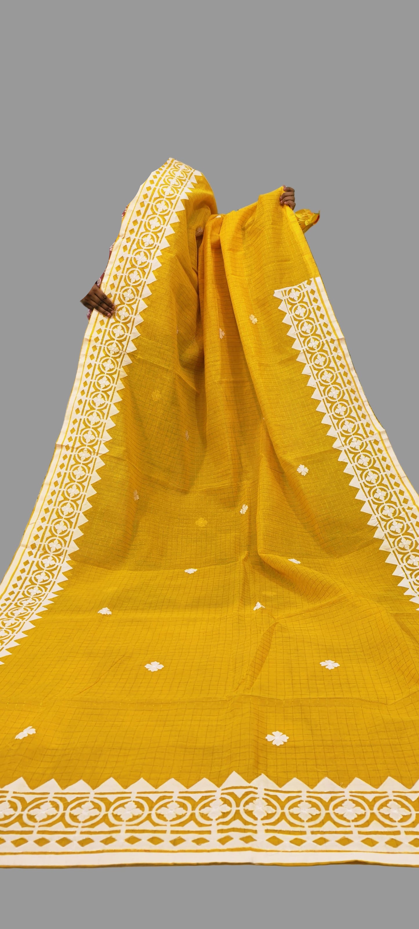 Mustard yellow saree with white border on a textured background
