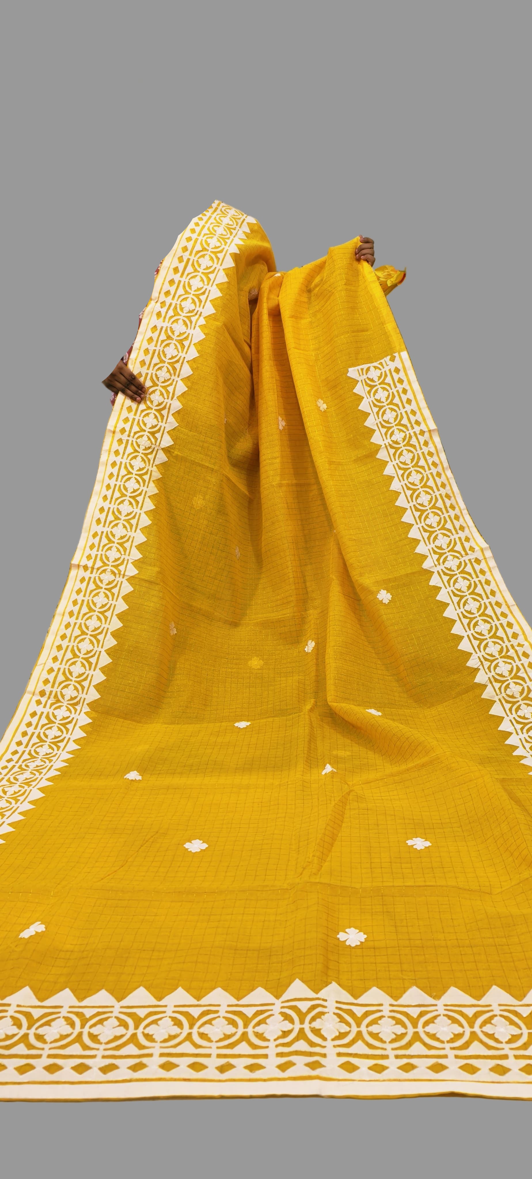 Mustard yellow saree with white border on a textured background