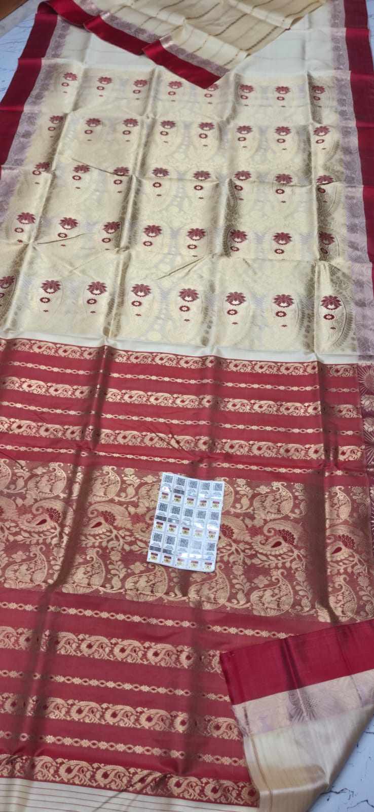 A cream and red Garad silk saree with intricate gold zari embroidery, featuring a wide red border with gold motifs and a matching red and gold pallu.